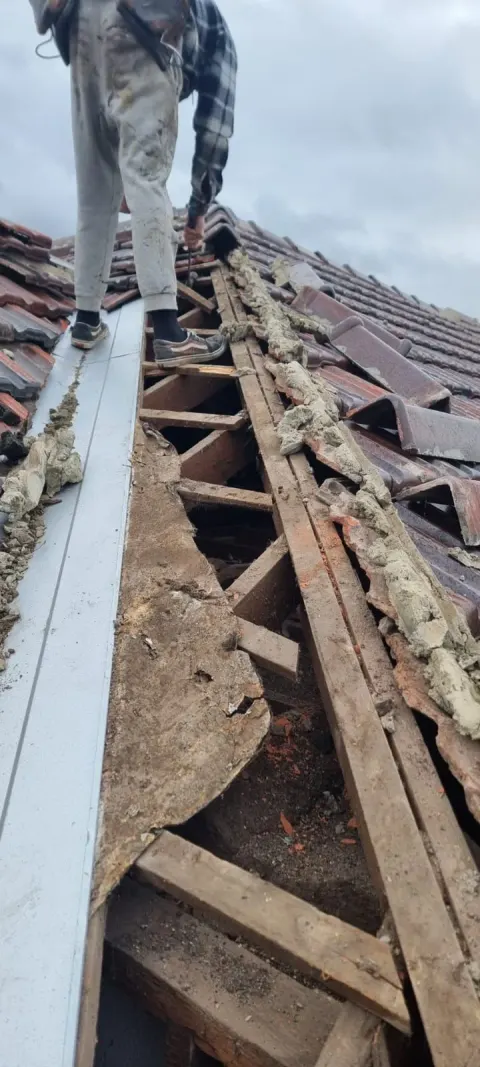 Re-bedding ridge caps — old bedding stripped back on a Melbourne roof