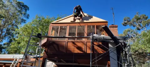 Cross-trade roofing and carpentry work on a scaffolded Melbourne home