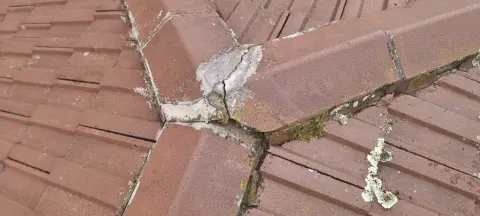 Close-up of cracked bedding mortar under a ridge cap on a Melbourne roof