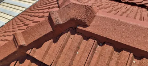 Ridge caps re-bedded and re-pointed on a terracotta roof in Melbourne