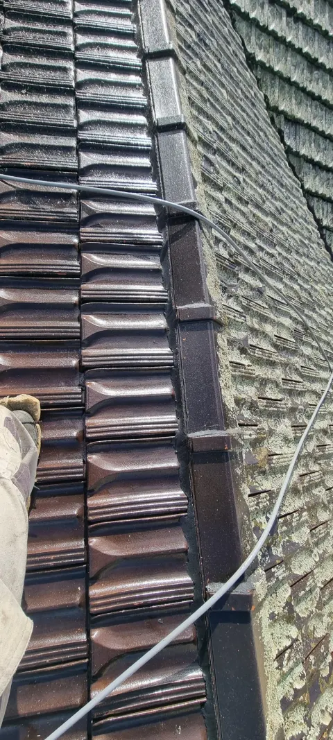 Moss and lichen being stripped from a tiled Melbourne roof by high-pressure cleaning