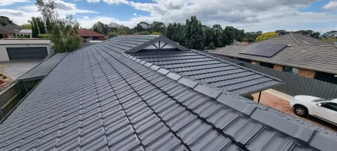 After: the same home with its tiled roof recoated in charcoal