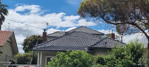 After: the same Melbourne home with its tiled roof restored and recoated in charcoal