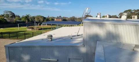 Cleaned commercial metal roof with a whirlybird and roof-access ladder on a Melbourne commercial site